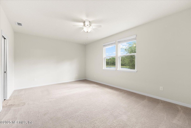 unfurnished room featuring ceiling fan, light colored carpet, baseboards, and visible vents