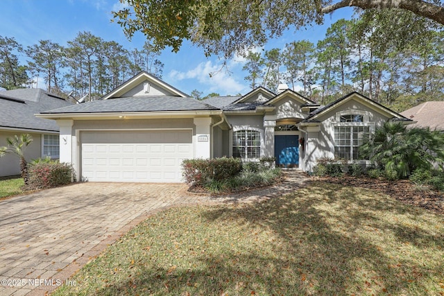 view of front facade featuring a garage, a front yard, decorative driveway, and stucco siding