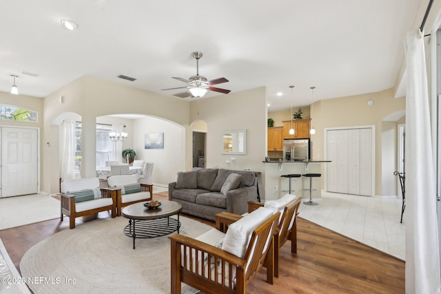 living area with arched walkways, visible vents, light wood finished floors, and recessed lighting