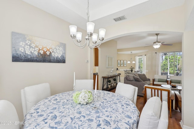 dining space with ceiling fan with notable chandelier, wood finished floors, visible vents, and lofted ceiling