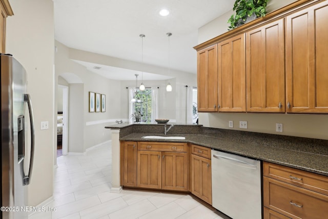 kitchen with a peninsula, brown cabinetry, stainless steel appliances, and a sink