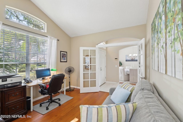 office area with arched walkways, a chandelier, wood finished floors, baseboards, and vaulted ceiling