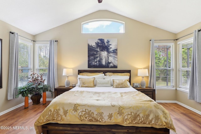 bedroom with multiple windows, vaulted ceiling, and wood finished floors