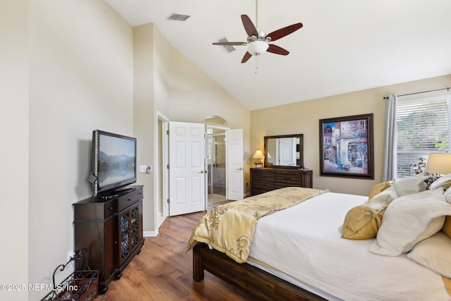 bedroom featuring high vaulted ceiling, wood finished floors, visible vents, baseboards, and ensuite bath