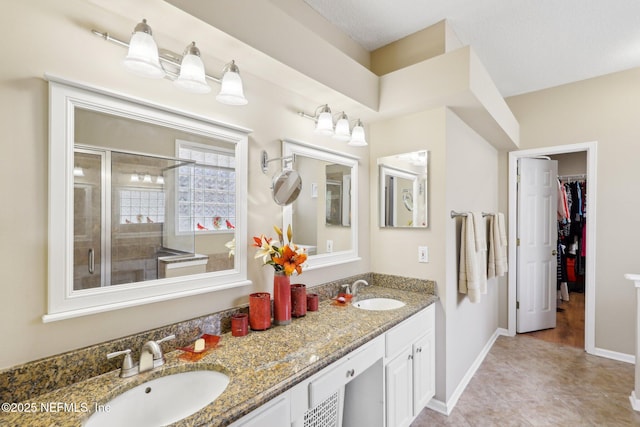 bathroom featuring double vanity, a shower stall, a spacious closet, and a sink