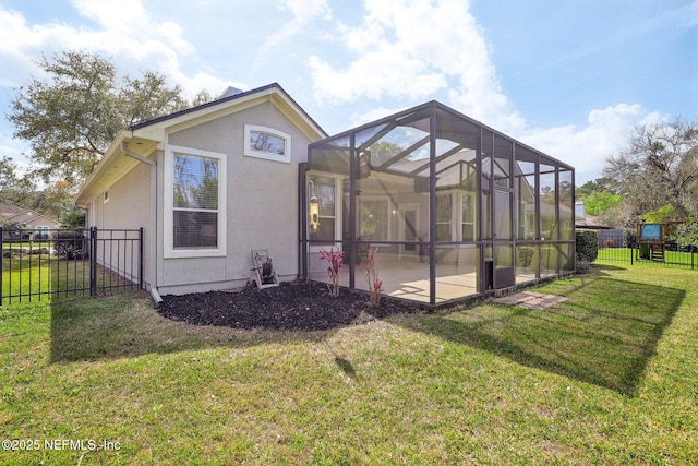 rear view of property with glass enclosure, fence, a yard, stucco siding, and a patio area