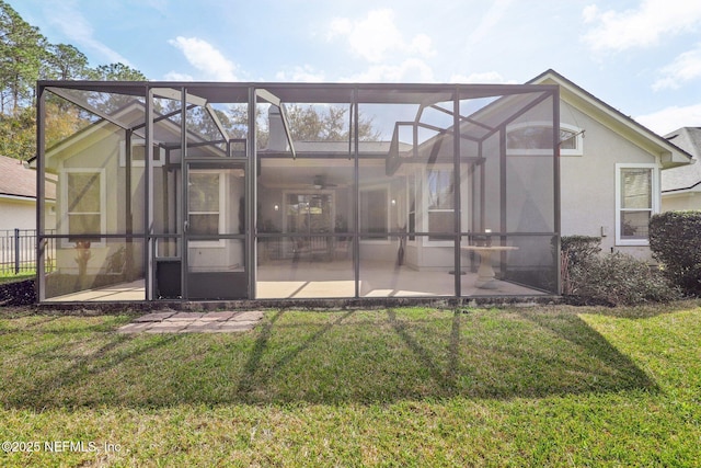 back of property with a lanai, a patio area, a yard, and stucco siding