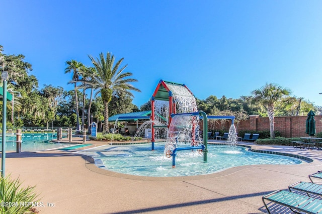 view of swimming pool featuring playground community and fence