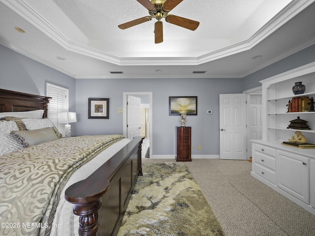 bedroom featuring a tray ceiling, crown molding, baseboards, and light carpet