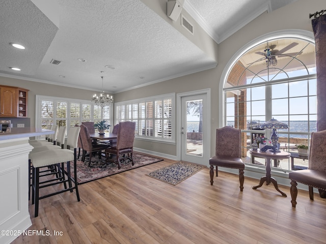 dining space with visible vents, plenty of natural light, light wood-style floors, and ornamental molding