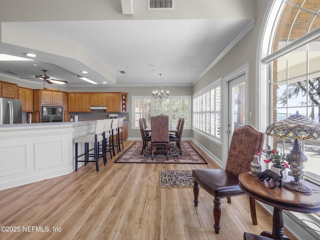 dining area with baseboards, visible vents, a textured ceiling, crown molding, and light wood-type flooring