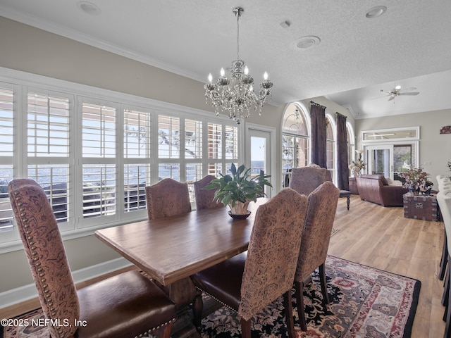 dining area with light wood finished floors, crown molding, baseboards, ceiling fan with notable chandelier, and a textured ceiling