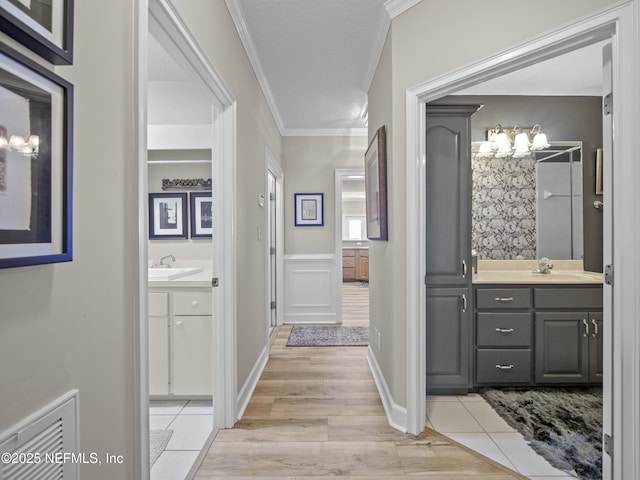 bathroom featuring visible vents, wainscoting, vanity, and ornamental molding