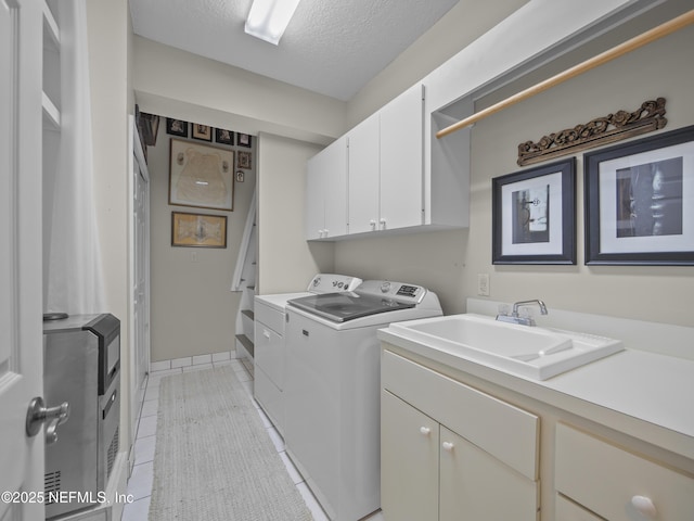 laundry area with washer and clothes dryer, a sink, a textured ceiling, cabinet space, and light tile patterned floors