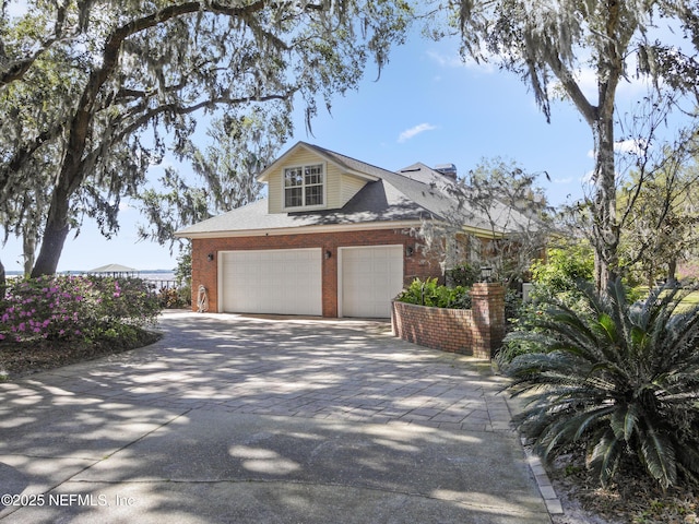 view of front facade featuring decorative driveway, brick siding, and a garage