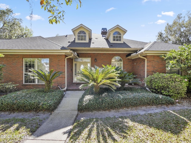 view of front of home featuring brick siding and roof with shingles