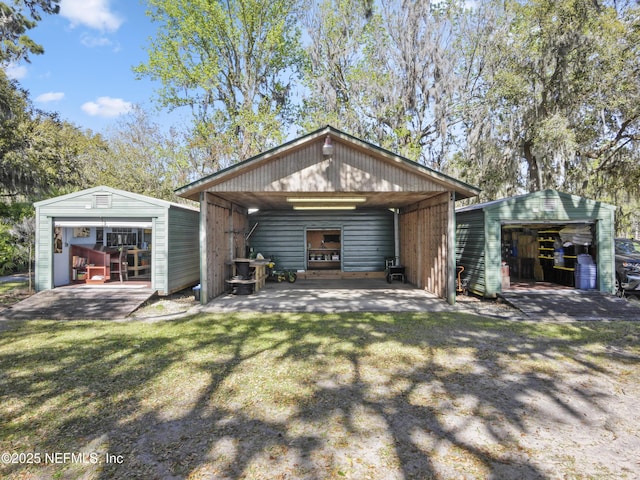 rear view of property featuring a lawn, a detached garage, and an outdoor structure