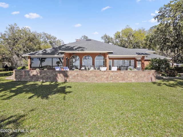 rear view of property featuring a yard and roof with shingles