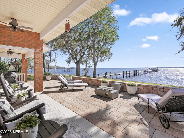 view of patio with a water view, an outdoor living space with a fire pit, and a ceiling fan