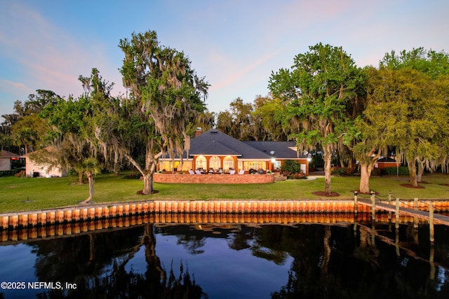 back of property featuring a water view, a lawn, and a tile roof