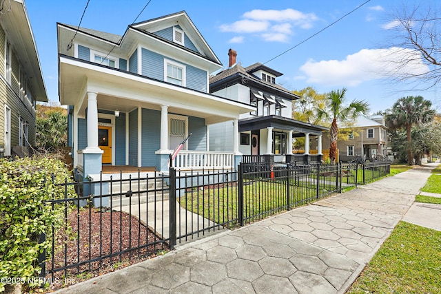 view of front of property with a porch, a front yard, and a fenced front yard