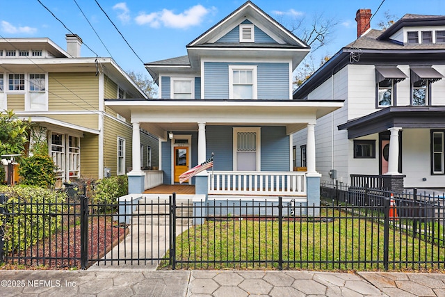 american foursquare style home featuring a fenced front yard and covered porch