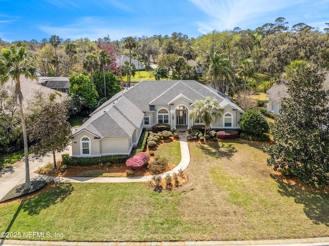 view of front of house featuring a shingled roof, a front yard, and stucco siding