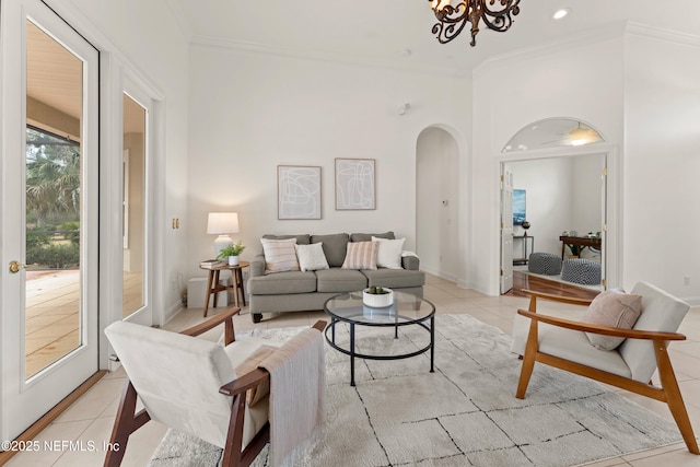 living area with light tile patterned floors, baseboards, arched walkways, ornamental molding, and a notable chandelier