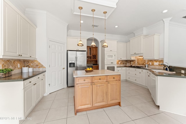 kitchen with light tile patterned floors, white appliances, a kitchen island, a sink, and crown molding