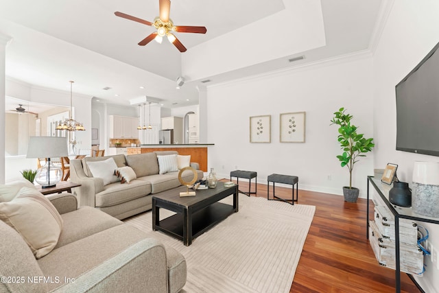 living room featuring ceiling fan with notable chandelier, a raised ceiling, and visible vents