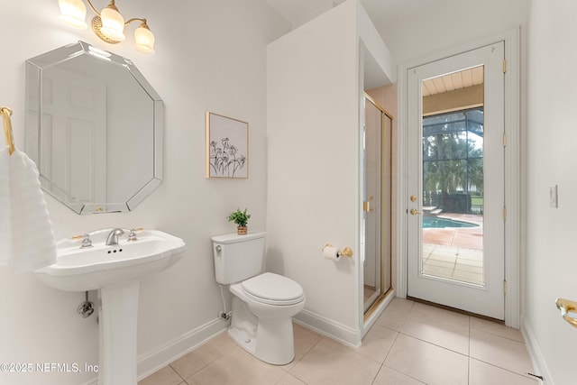 bathroom with toilet, a sink, baseboards, tile patterned floors, and a stall shower