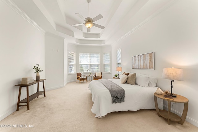 carpeted bedroom featuring a ceiling fan, a tray ceiling, ornamental molding, and baseboards