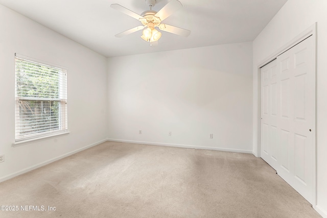 unfurnished bedroom with light carpet, ceiling fan, baseboards, and a closet