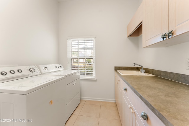 laundry room with light tile patterned floors, cabinet space, a sink, separate washer and dryer, and baseboards