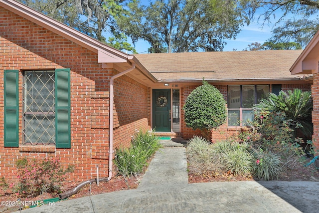 entrance to property with brick siding and roof with shingles