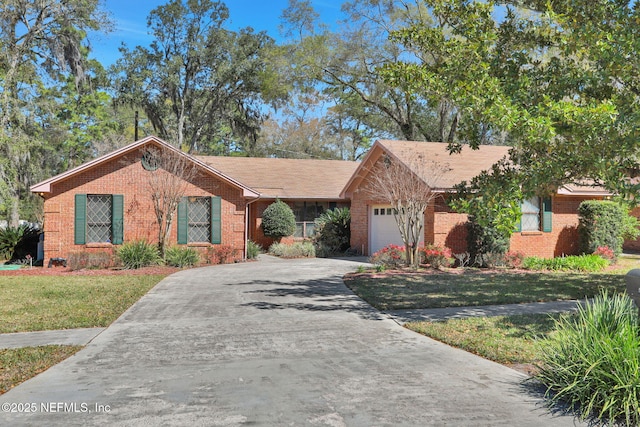 ranch-style house featuring a garage, driveway, brick siding, and a front lawn