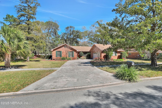 single story home with a garage, concrete driveway, brick siding, and a front lawn