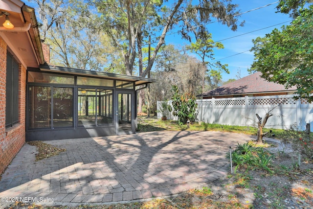 view of patio featuring a sunroom and fence