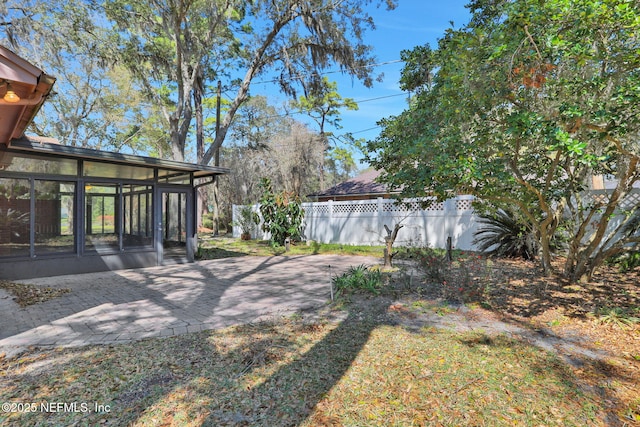 view of yard featuring a sunroom, fence, and a patio