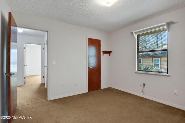 unfurnished bedroom with carpet, baseboards, and a textured ceiling