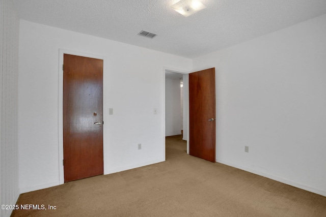 unfurnished bedroom with visible vents, a textured ceiling, and light colored carpet