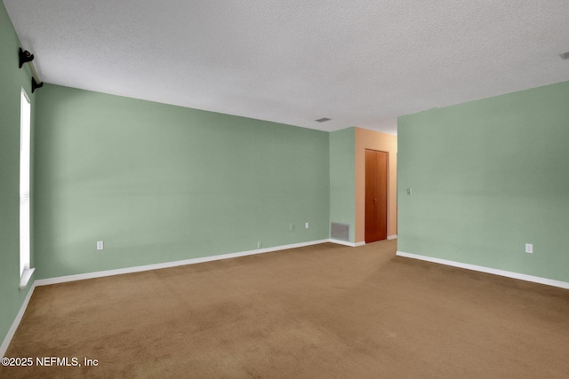 carpeted spare room with visible vents, a textured ceiling, and baseboards