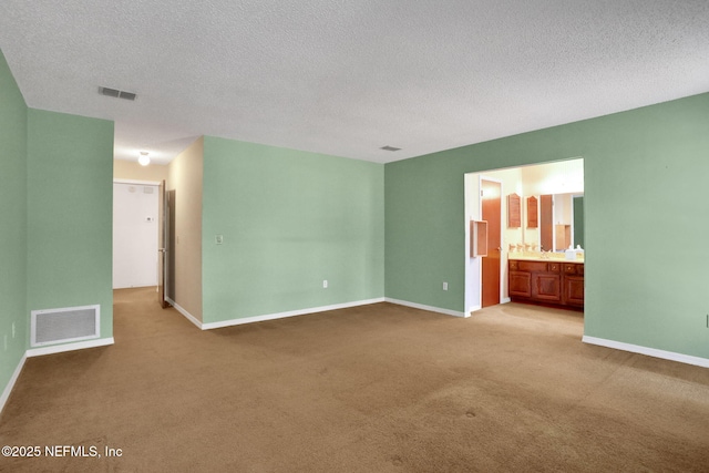 carpeted empty room featuring baseboards, visible vents, and a textured ceiling