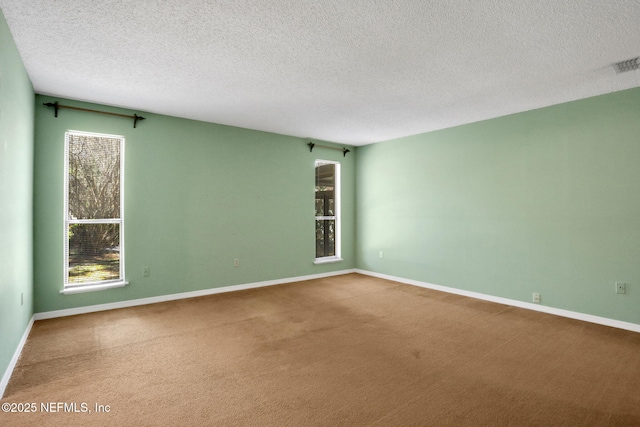 empty room with carpet flooring, visible vents, and baseboards