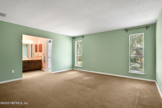 unfurnished bedroom with a textured ceiling, multiple windows, carpet flooring, and baseboards