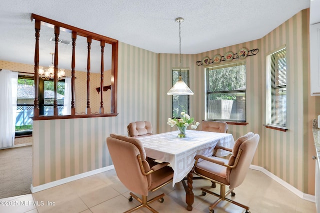 tiled dining space featuring a textured ceiling, a healthy amount of sunlight, baseboards, and wallpapered walls