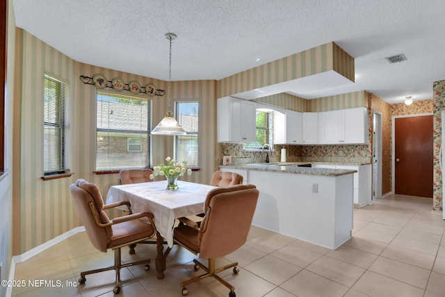 dining area with wallpapered walls, baseboards, visible vents, a textured ceiling, and light tile patterned flooring