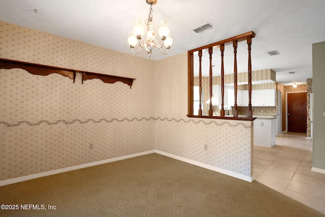 empty room featuring light tile patterned floors, visible vents, a chandelier, baseboards, and wallpapered walls