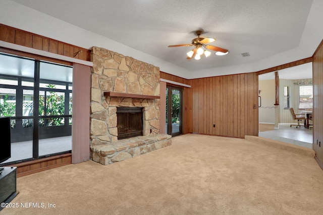 unfurnished living room with visible vents, ceiling fan, carpet, a textured ceiling, and a fireplace