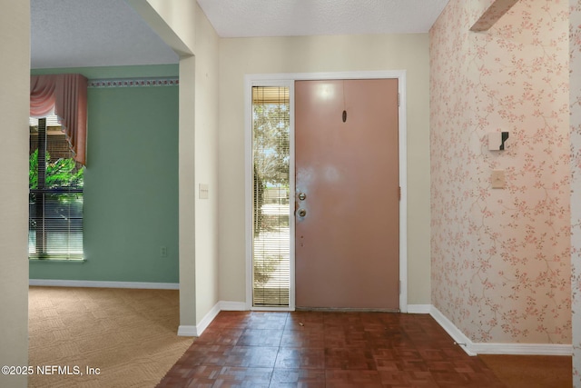 entrance foyer featuring a textured ceiling, baseboards, and wallpapered walls